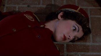Movie still from “Clue” (1985), directed by Jonathan Lynn – A woman in a uniform laying on a brick wall; Close Up shot, Overhead angle