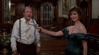 Movie still from “Clue” (1985), directed by Jonathan Lynn – A man and a woman are holding a gun; Medium shot, Over the shoulder angle