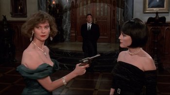 Movie still from “Clue” (1985), directed by Jonathan Lynn – A woman holding a gun in front of two other women; Medium shot, Over the shoulder angle