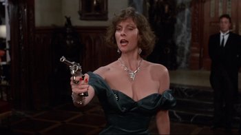 Movie still from “Clue” (1985), directed by Jonathan Lynn – A woman in a black dress holding a gun; Close Up shot, Low angle