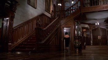 Movie still from “Clue” (1985), directed by Jonathan Lynn – A woman in a black dress entering a house; Extreme Wide shot, Low angle