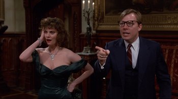 Movie still from “Clue” (1985), directed by Jonathan Lynn – A man and a woman are standing next to each other; Medium shot, Over the shoulder angle