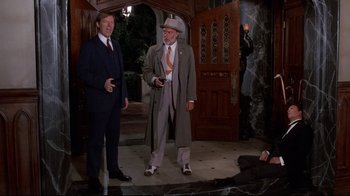 Movie still from “Clue” (1985), directed by Jonathan Lynn – Two men dressed in suits and hats are standing in front of a door; Wide shot, High angle