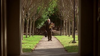 Movie still from “Clueless” (1995), directed by Amy Heckerling – An older man in a business suit is reading a newspaper; Wide shot, Low angle