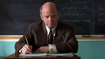 Movie still from “Clueless” (1995), directed by Amy Heckerling – A man in a suit and tie writing on a notebook; Close Up shot, Low angle