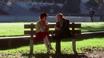 Movie still from “Clueless” (1995), directed by Amy Heckerling – A man and a woman sitting on a park bench; Wide shot, Low angle