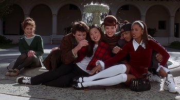 Movie still from “Clueless” (1995), directed by Amy Heckerling – A group of young people sitting on the ground in front of a fountain; Wide shot, High angle
