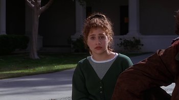 Movie still from “Clueless” (1995), directed by Amy Heckerling – A woman sitting on the ground in front of a building; Close Up shot, Over the shoulder angle