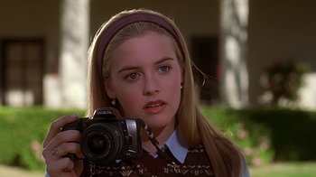 Movie still from “Clueless” (1995), directed by Amy Heckerling – A woman holding a camera in front of her face; Close Up shot, Low angle
