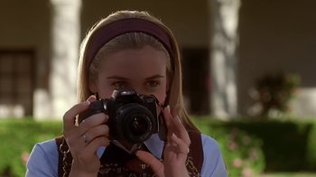 Movie still from “Clueless” (1995), directed by Amy Heckerling – A woman taking a picture with a camera; Close Up shot, Over the shoulder angle