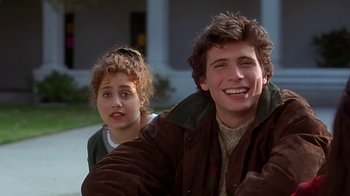 Movie still from “Clueless” (1995), directed by Amy Heckerling – A man and a woman sitting next to each other on the street; Medium shot, Over the shoulder angle
