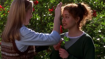 Movie still from “Clueless” (1995), directed by Amy Heckerling – A woman giving a flower to another woman; Close Up shot, Over the shoulder angle