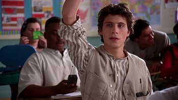 Movie still from “Clueless” (1995), directed by Amy Heckerling – A young man raises his hand in front of a class; Close Up shot, Low angle