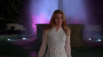 Movie still from “Clueless” (1995), directed by Amy Heckerling – A girl in a white dress standing in front of a purple light; Medium shot, Low angle