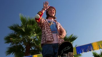 Movie still from “Clueless” (1995), directed by Amy Heckerling – A man with a hat on holding a skateboard; Medium shot, Low angle
