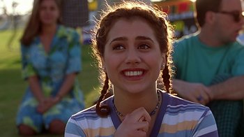 Movie still from “Clueless” (1995), directed by Amy Heckerling – A girl with pigtails smiles for the camera; Close Up shot, Over the shoulder angle