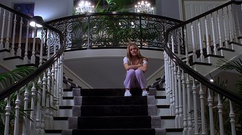 Movie still from “Clueless” (1995), directed by Amy Heckerling – A woman sitting on top of a set of stairs; Wide shot, Low angle