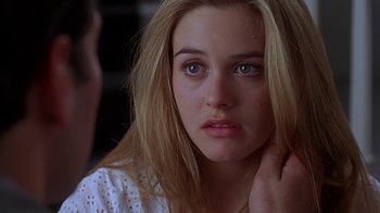 Movie still from “Clueless” (1995), directed by Amy Heckerling – A young woman looking at the camera while holding her hand to her face; Close Up shot, Over the shoulder angle