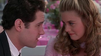 Movie still from “Clueless” (1995), directed by Amy Heckerling – A man and a woman sitting next to each other in front of pink flowers; Close Up shot, Over the shoulder angle