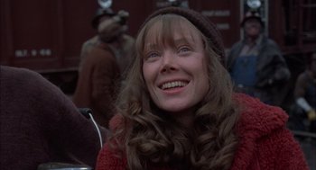 Movie still from “Coal Miner's Daughter” (1980), directed by Michael Apted – A woman with long brown hair wearing a red sweater; Close Up shot, Low angle