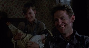 Movie still from “Coal Miner's Daughter” (1980), directed by Michael Apted – A man holding a baby in his arms and smiling; Close Up shot, Low angle