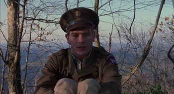 Movie still from “Coal Miner's Daughter” (1980), directed by Michael Apted – A man in a military uniform sitting in front of a tree; Medium shot, High angle