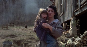 Movie still from “Coal Miner's Daughter” (1980), directed by Michael Apted – A woman holding a young girl in her arms in front of a barn; Close Up shot, High angle