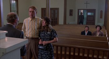 Movie still from “Coal Miner's Daughter” (1980), directed by Michael Apted – A man and a woman standing next to each other in a church; Wide shot, Over the shoulder angle