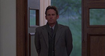 Movie still from “Coal Miner's Daughter” (1980), directed by Michael Apted – A man in a suit and tie standing in front of a door; Medium shot, Over the shoulder angle