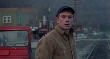 Movie still from “Coal Miner's Daughter” (1980), directed by Michael Apted – A man wearing a hat standing in front of a red truck; Close Up shot, Over the shoulder angle