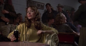 Movie still from “Coal Miner's Daughter” (1980), directed by Michael Apted – A woman sitting at a table in front of a group of people; Medium shot, Over the shoulder angle