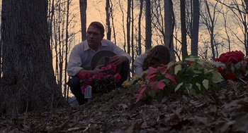 Movie still from “Coal Miner's Daughter” (1980), directed by Michael Apted – A man kneeling down next to a woman holding flowers; Medium shot, Low angle