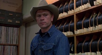 Movie still from “Coal Miner's Daughter” (1980), directed by Michael Apted – A man wearing a cowboy hat standing in front of shelves; Close Up shot, Over the shoulder angle