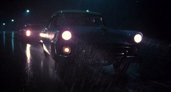 Movie still from “Coal Miner's Daughter” (1980), directed by Michael Apted – A car driving down a wet road in the rain at night; Wide shot, Low angle