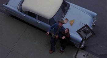 Movie still from “Coal Miner's Daughter” (1980), directed by Michael Apted – A man and a woman standing in front of an old car; Wide shot, Overhead angle