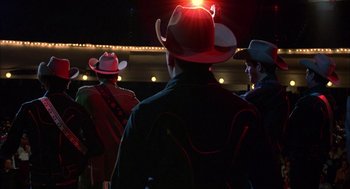 Movie still from “Coal Miner's Daughter” (1980), directed by Michael Apted – A group of men wearing cowboy hats on a stage; Medium shot, Low angle