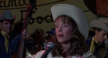 Movie still from “Coal Miner's Daughter” (1980), directed by Michael Apted – A woman in a white cowboy hat holding a microphone; Close Up shot, Over the shoulder angle