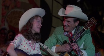 Movie still from “Coal Miner's Daughter” (1980), directed by Michael Apted – A man and a woman wearing cowboy hats and holding guitars; Medium shot, Over the shoulder angle