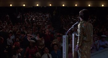 Movie still from “Coal Miner's Daughter” (1980), directed by Michael Apted – A crowd of people watching a man speak at an event; Wide shot, High angle