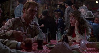 Movie still from “Coal Miner's Daughter” (1980), directed by Michael Apted – A group of people sitting at a table with drinks; Medium shot, Over the shoulder angle
