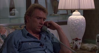 Movie still from “Coal Miner's Daughter” (1980), directed by Michael Apted – A man sitting on a couch talking on a phone; Close Up shot, Low angle