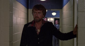 Movie still from “Coal Miner's Daughter” (1980), directed by Michael Apted – A man with a beard is walking down a hallway; Medium shot, Over the shoulder angle