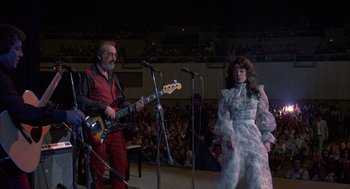 Movie still from “Coal Miner's Daughter” (1980), directed by Michael Apted – A man and a woman on stage with a microphone; Wide shot, Low angle