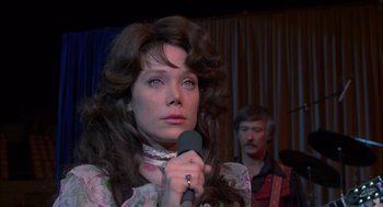 Movie still from “Coal Miner's Daughter” (1980), directed by Michael Apted – A woman holding a microphone in front of a man; Close Up shot, Over the shoulder angle