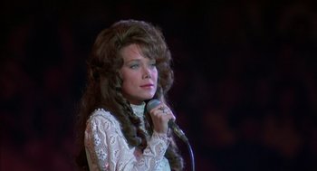Movie still from “Coal Miner's Daughter” (1980), directed by Michael Apted – A woman in a white shirt is holding a microphone; Close Up shot, Low angle