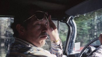 Movie still from “Cockfighter” (1974), directed by Monte Hellman – A man with glasses sitting in the driver's seat of a car; Close Up shot, Low angle