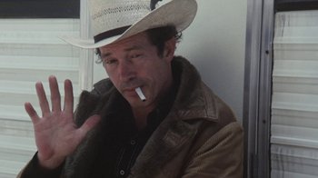 Movie still from “Cockfighter” (1974), directed by Monte Hellman – A man wearing a cowboy hat smoking a cigarette; Close Up shot, High angle