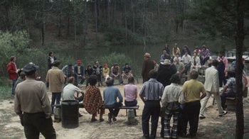 Movie still from “Cockfighter” (1974), directed by Monte Hellman – A group of people standing around a body of water; Extreme Wide shot, High angle