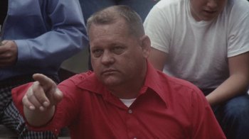 Movie still from “Cockfighter” (1974), directed by Monte Hellman – A person wearing a red shirt; Close Up shot, High angle