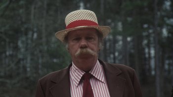 Movie still from “Cockfighter” (1974), directed by Monte Hellman – An older man wearing a straw hat and a striped tie; Close Up shot, Low angle
